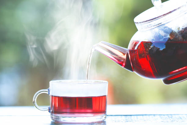 el té de hierbas saludable se vierte desde la tetera en una taza de vidrio - rosa salvaje fotografías e imágenes de stock