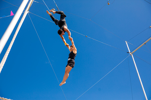 Trapeze artists swinging together in the sky