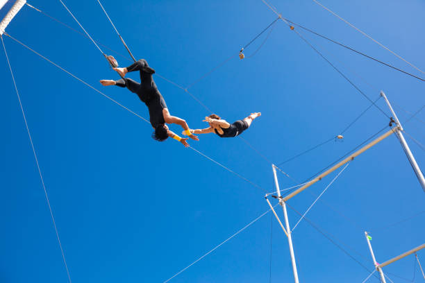 artistes de trapèze volant dans le ciel bleu - thrusting photos et images de collection