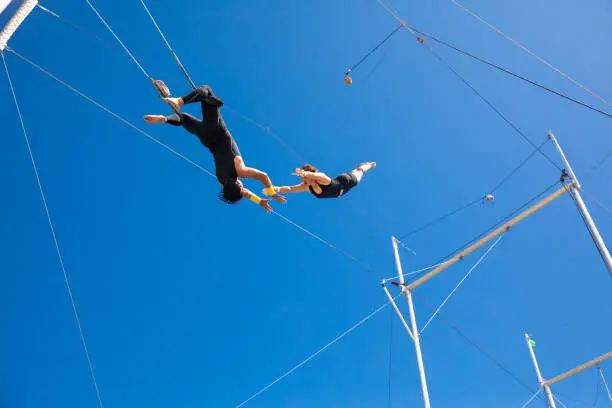 Photo of Trapeze artists flying in the blue sky