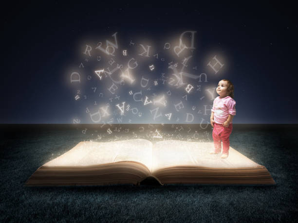 istock Little girl looking up on magical book with glowing letters 1179473749