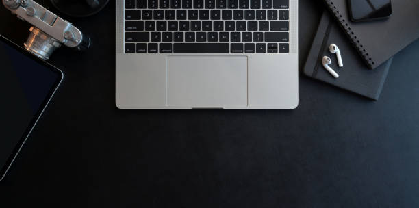 istock Top view of dark modern workplace with open laptop computer and office supplies on black leather desk 1179480734