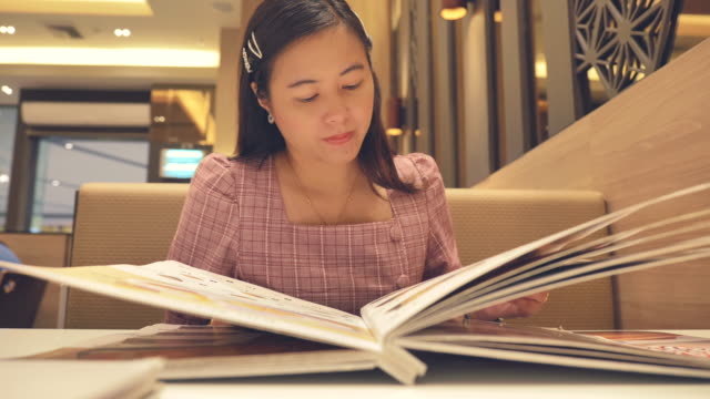 Scene slow motion of young asian woman reading a menu at restaurant, Concept of holiday end of week, Lifestyle of asian woman