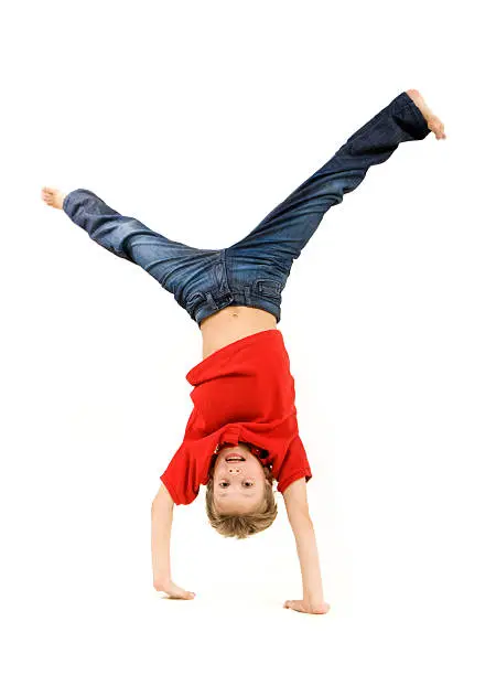 Photo of Boy in red shirt and jeans doing a handstand