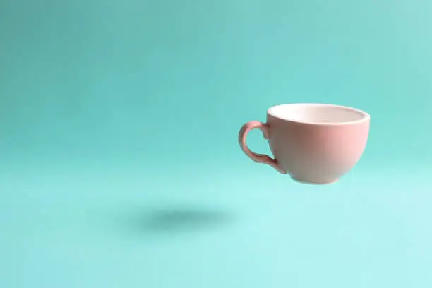 Photo of Pink mug cup floating on green background