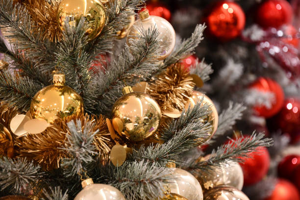 istock Closeup of golden Christmas balls with reflective surface. Artificial Christmas tree branches decorated with golden tinsel garlands and blurred red balls on bokeh background. New Year backdrop 1179493882