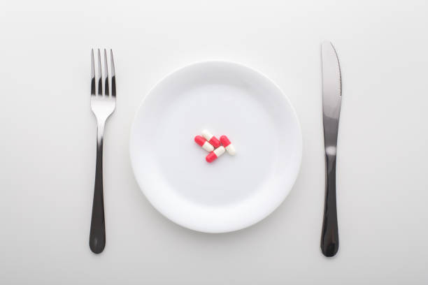 istock Capsule pills on white plate with fork and knife 1179496523