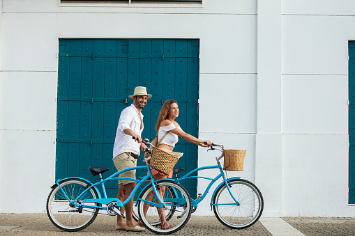 Latin ethnicity couple ages 25-35 are riding bicycles through the streets of Cartagena de Indias