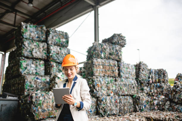 Female Resource Recovery Specialist Using Digital Tablet Close-up of female environmental expert using digital tablet for notes while conducting satisfying onsite inspection of recycling facility. social responsibility photos stock pictures, royalty-free photos & images