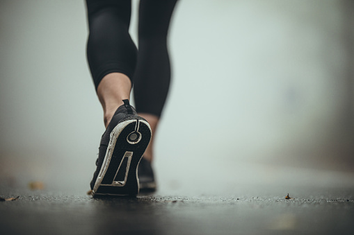 Close up of unrecognizable athlete walking on the road during misty day. Copy space.