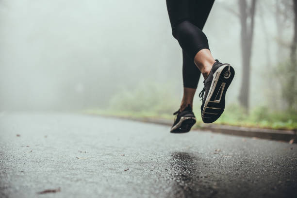 istock Unrecognizable athlete jogging on the road during rainy day. 1179509323