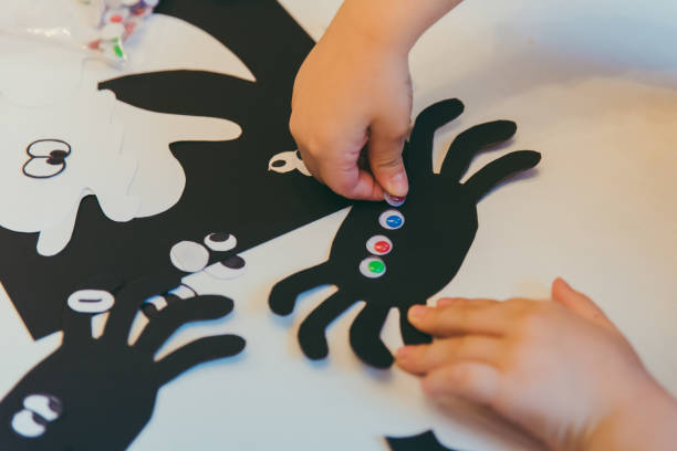 jeune mère avec le fils d'enfant en bas âge faisant des araignées d'artisanat pour le temps de famille de vacances d'halloween - spider mum photos et images de collection