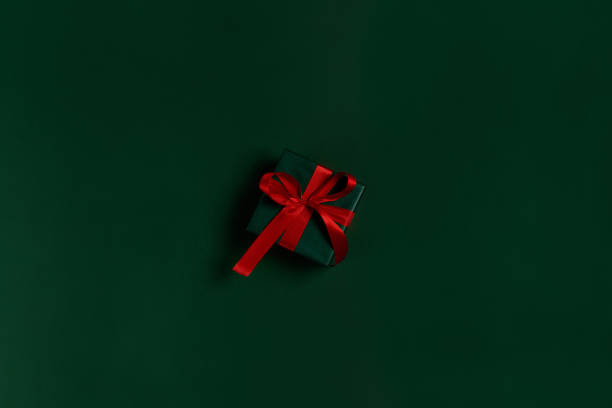 istock Green gift box with red  ribbon on green background 1179513097