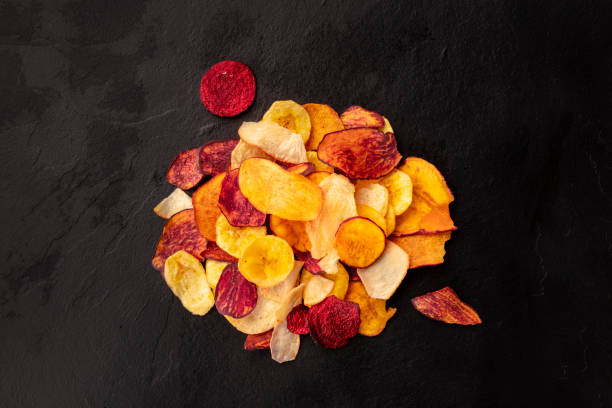 istock Dry fruit and vegetable chips, healthy vegan snack, a mixed heap on a black background 1179514364