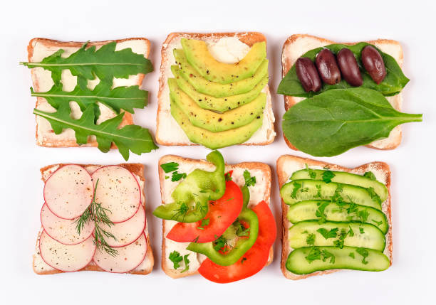 istock Set with toast bread and different vegan toppings on white background, top view. Toasts with avocado, spinach, arugula and other vegetables ingridients. Healthy snack or vegan food concept 1179515396