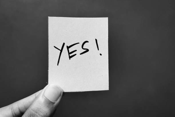 Hand holding a paper card with the word YES