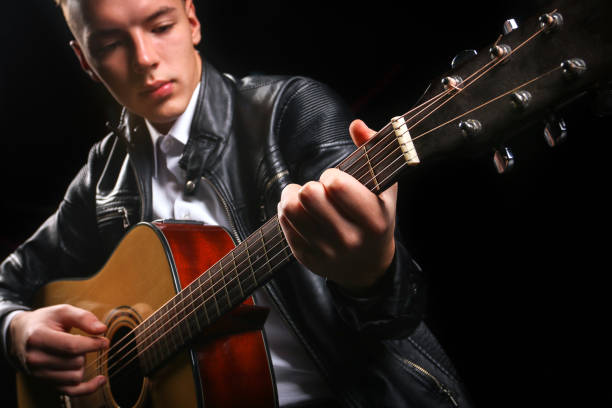 istock Young men playing the guitar with black background 1179516653