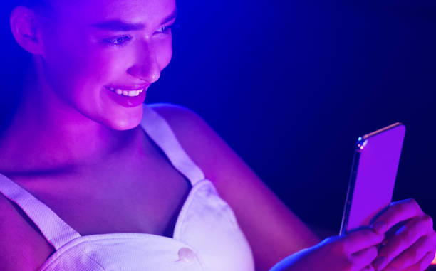 istock Young woman using smartphone with blue and pink neon lights 1179519638
