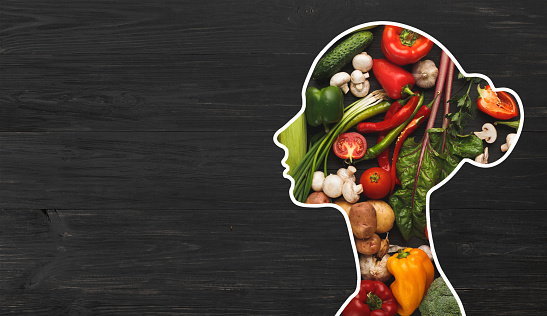 Food for health. Woman silhouette with fresh vegetables in her body on wooden background with copy space, panorama