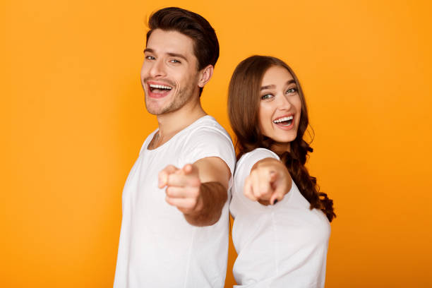 Joyful young couple pointing fingers at camera