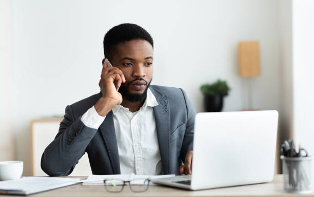 istock Focused afro businessman talking on cellphone and working on laptop 1179524114