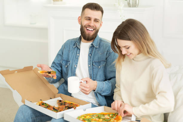 istock Young couple eating pizza and drinking tea, having lunch 1179524388