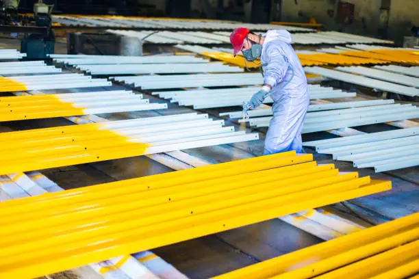 man painting metal in factory