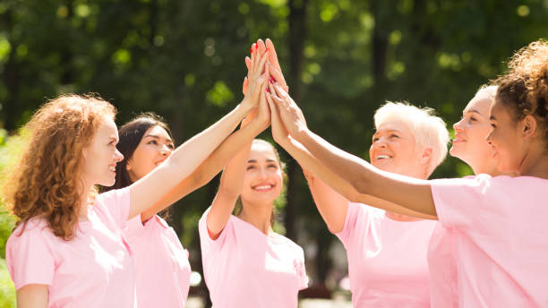 Breast Cancer Volunteer Group Of Multiethnic Women Giving High-Five Outdoor Positive Breast Cancer Volunteer Group Of Multiethnic Women In Pink T-Shirts Giving High Five Outdoor. Panorama, Selective Focus food chain stock pictures, royalty-free photos & images