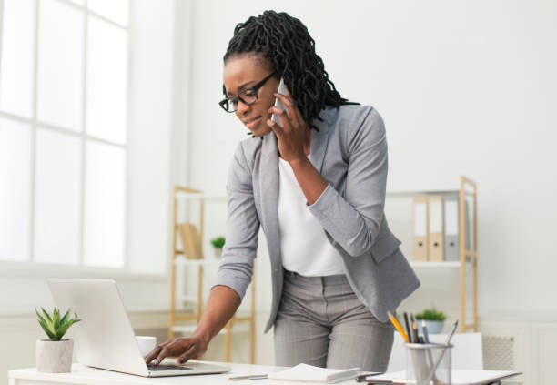 istock Afro Lady Talking On Cellphone Typing On Laptop In Office 1179526592