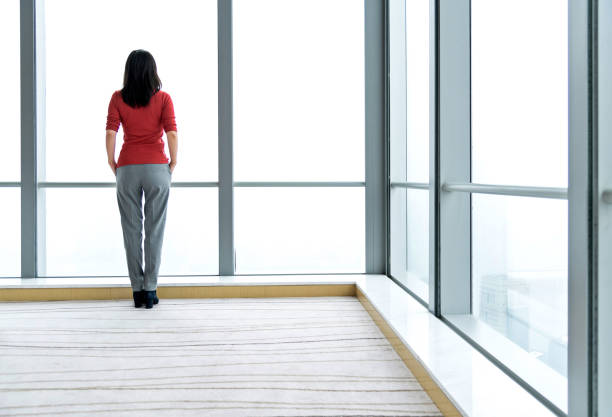 istock Woman standing and looking through the window 1179527091