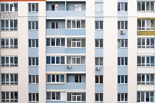 Facade of condominium. Multi-storey residential building. Abstract texture. Wall with windows and balconies of Russian and Ukrainian design, architecture background