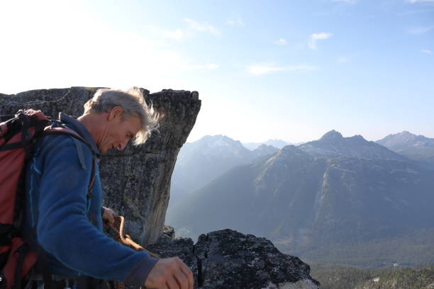 istock Mountaineer standing on cliff adjusts climbing rope 1179533275