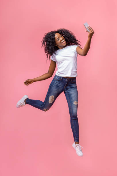 chica negra loca haciendo selfie mientras salta en el aire - female young women red hair full length fotografías e imágenes de stock