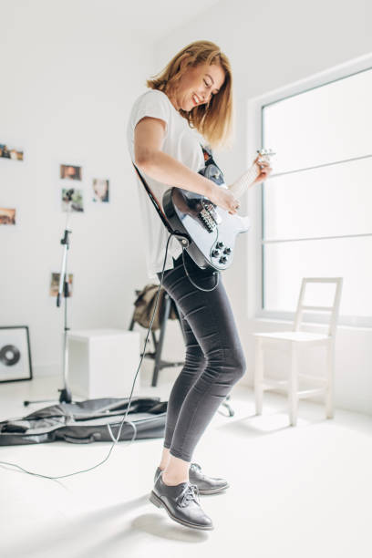 istock Beautiful lady playing electric guitar in music studio alone 1179535606