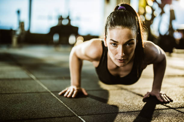 istock Young athletic woman exercising push-ups in a gym. 1179536230