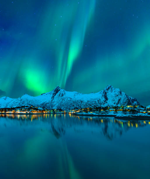 Northern Lights or Aurora Borealis in the night sky over the town of Svolvaer in the Lofoten Northern Lights, polar light or Aurora Borealis in the night sky over the town of Svolvaer in the Lofoten in Norway with a reflection in the fjord in the foreground. The mountains in the background are covered in snow and ice. norway aurora borealis aurora polaris fjord stock pictures, royalty-free photos & images