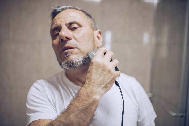 istock The older man trims his beard himself 1179542705