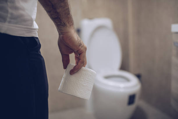 An elderly man holds toilet paper in his hand