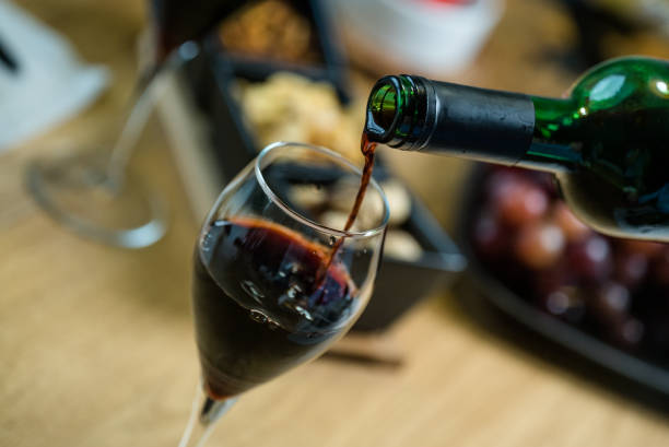 Pouring wine into glass and food background