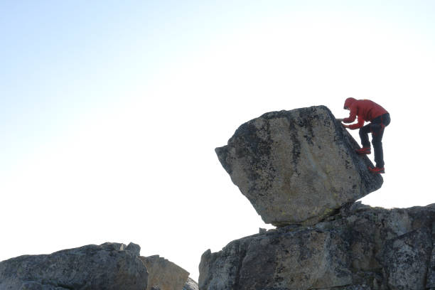 istock Young man scrambles up boulder in the morning 1179548096