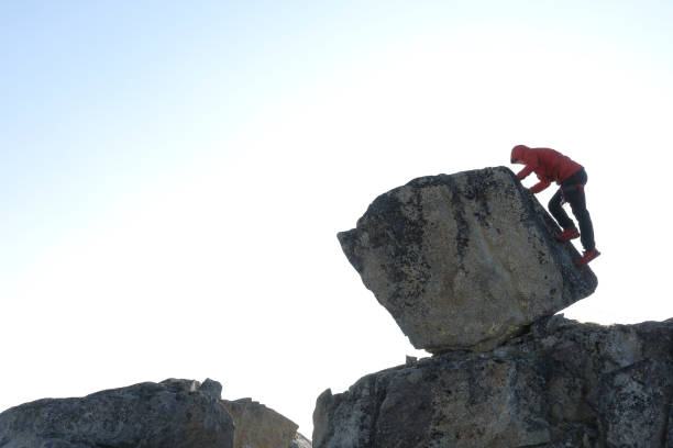 istock Young man scrambles up boulder in the morning 1179548098