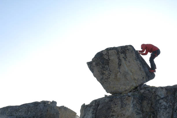 istock Young man scrambles up boulder in the morning 1179548104