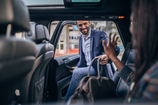 Man getting in back seat of a car Man and woman, multi-ethnic couple ridding on back seat of a car, ride sharing in city. crowdsourced taxi photos stock pictures, royalty-free photos & images
