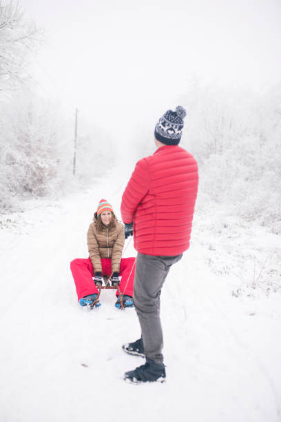 pares novos que sledding e que apreciam no dia de inverno - pair couple cheerful laughing - fotografias e filmes do acervo