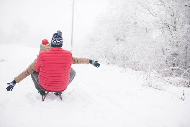 pares novos que sledding e que apreciam no dia de inverno - pair couple cheerful laughing - fotografias e filmes do acervo