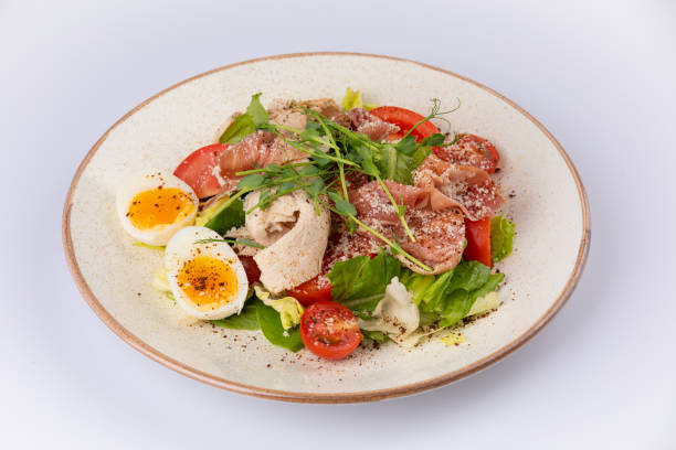 istock a bowl of fresh lettuce salad with tomatoes eggs prosciutto over white. 1179554102