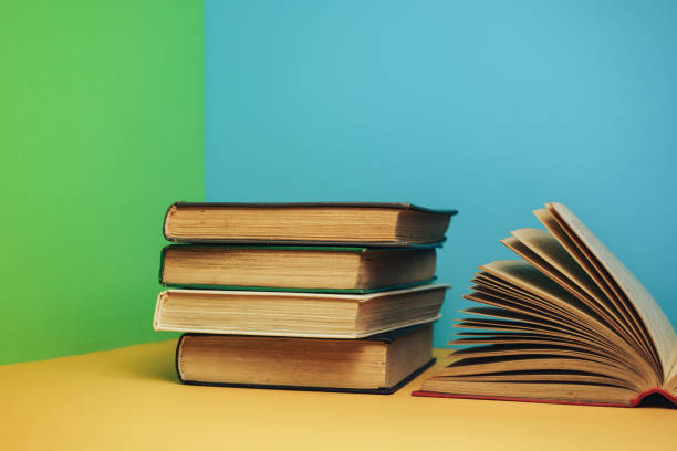 istock Beautiful open red books on a yellow table and green blue background. 1179554301