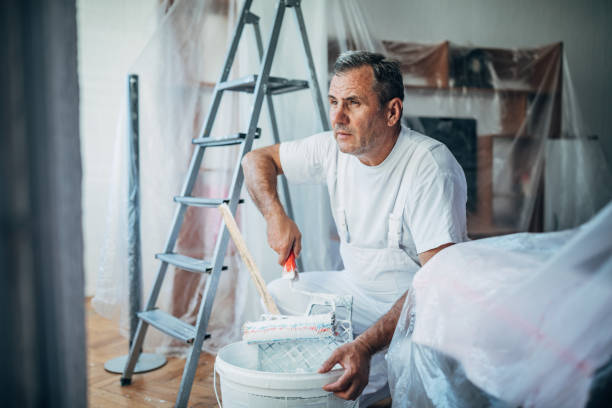 istock Painter is mixing colors in bucket at home 1179554841