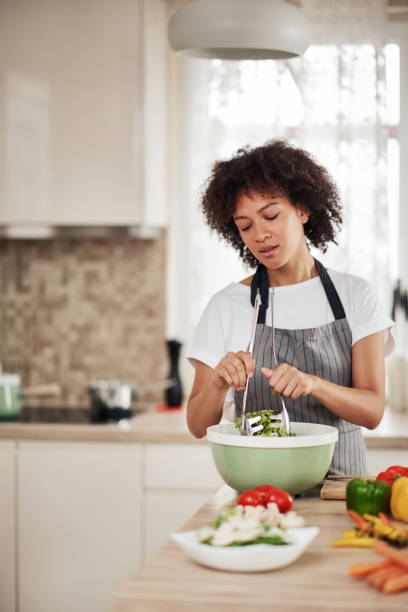 istock Woman mixing salad while standing in kitchen. 1179556353