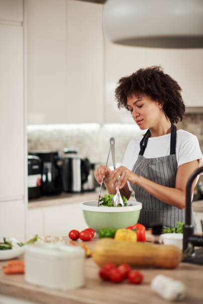 istock Woman mixing salad while standing in kitchen. 1179557296